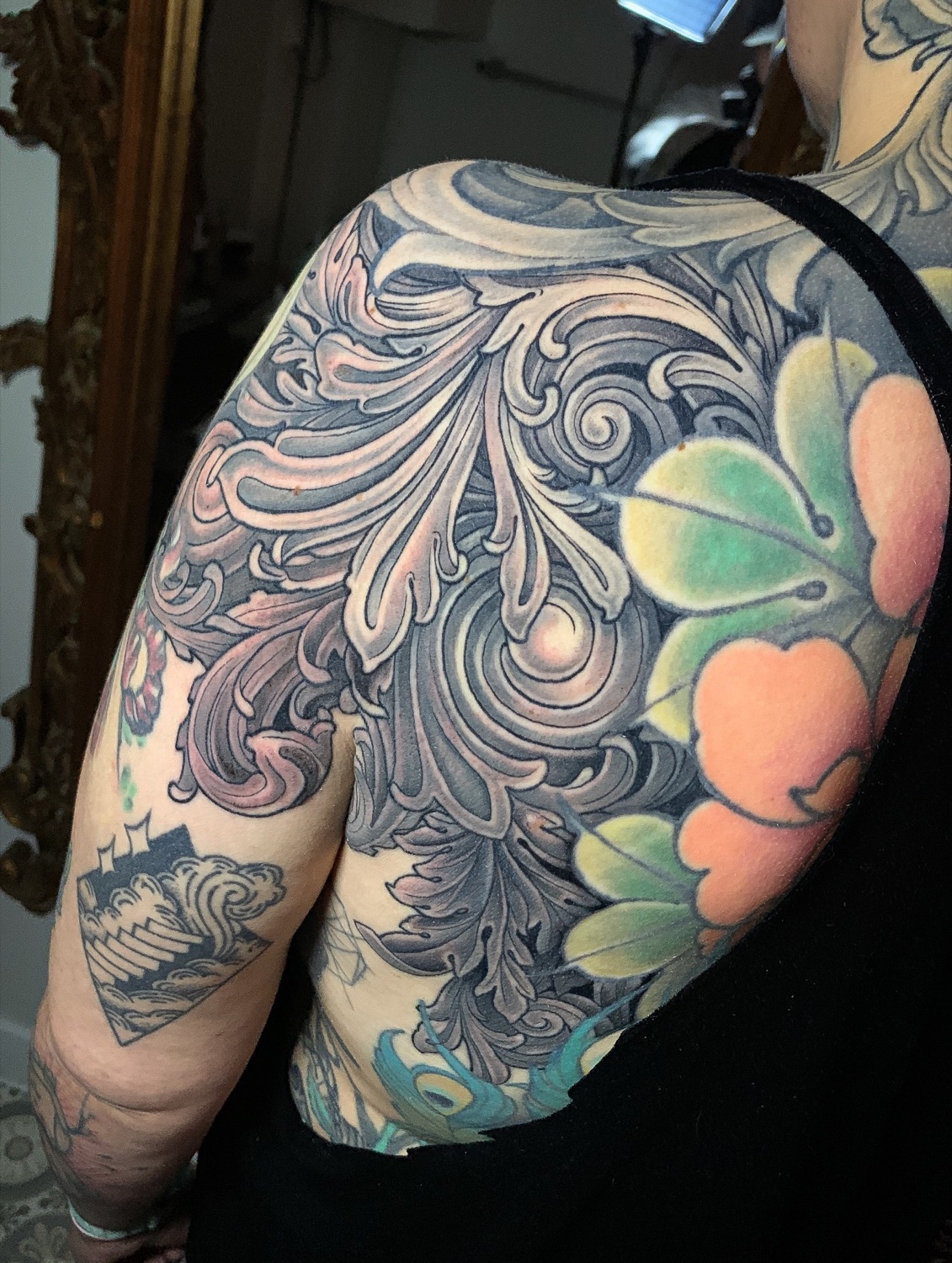 Tatouage ornemental filigrane et fleurs en couleur sur l'épaule